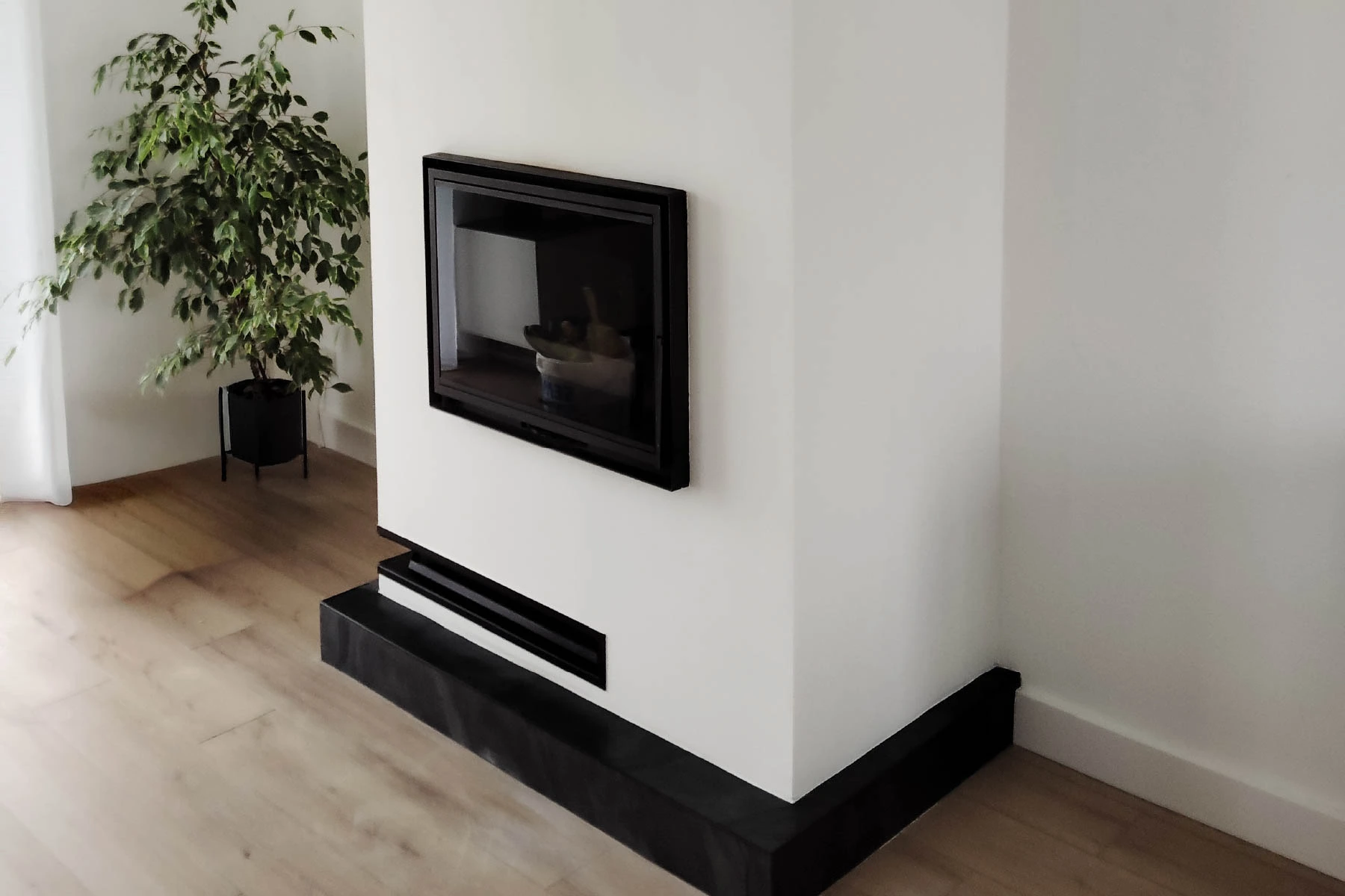 Création d'un habillage sur mesure en placo peint en blanc pour un insert à granulés moderne avec socle noir par un artisan près de Nancy
