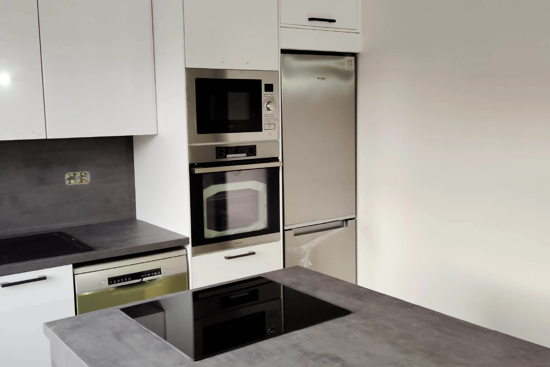 Installation complète d'une cuisine équipée blanche avec électroménager encastré et îlot central gris dans une maison rénovée à Nancy artisan 54