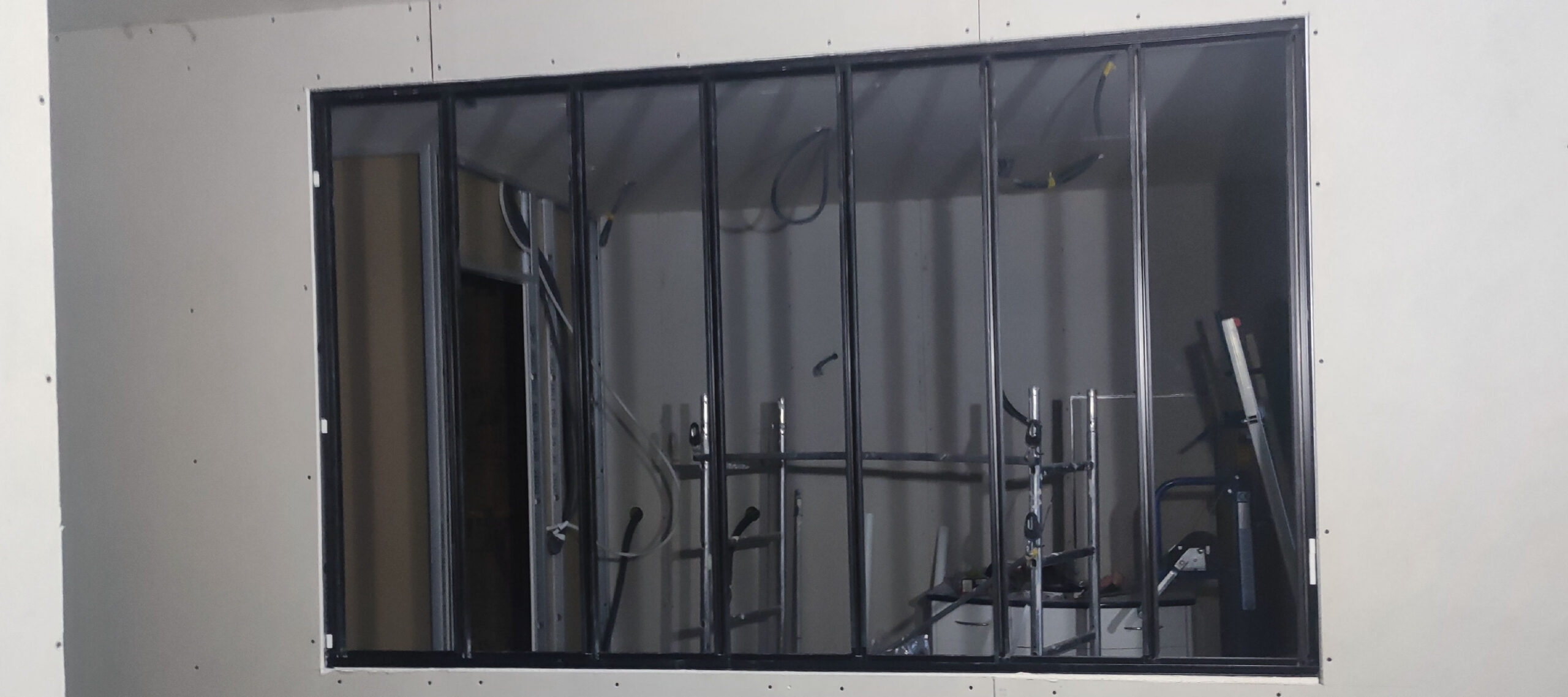 Mur en placo brut avec installation d'une verrière d'atelier intérieure noire avant finitions