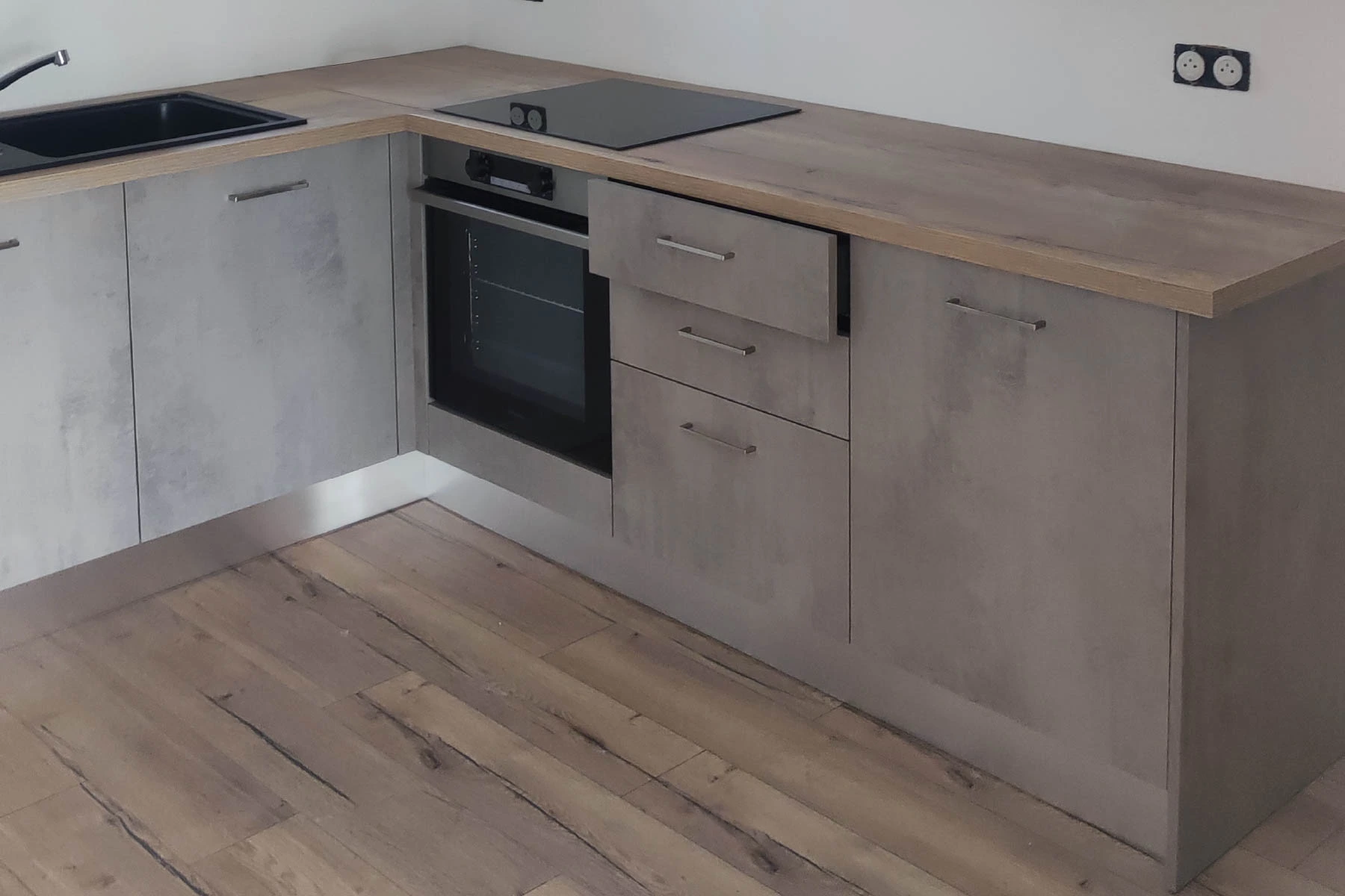 Rénovation d'une cuisine moderne avec meubles bas gris effet béton, plan de travail en bois et pose de sol stratifié par un artisan à Nancy